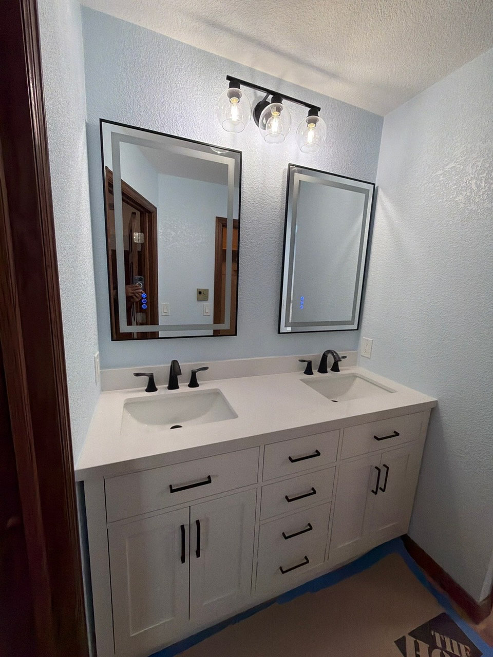 Double vanity with white cabinets and black hardware after bathroom remodeling